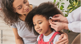 Doctor putting on hearing aid for young girl