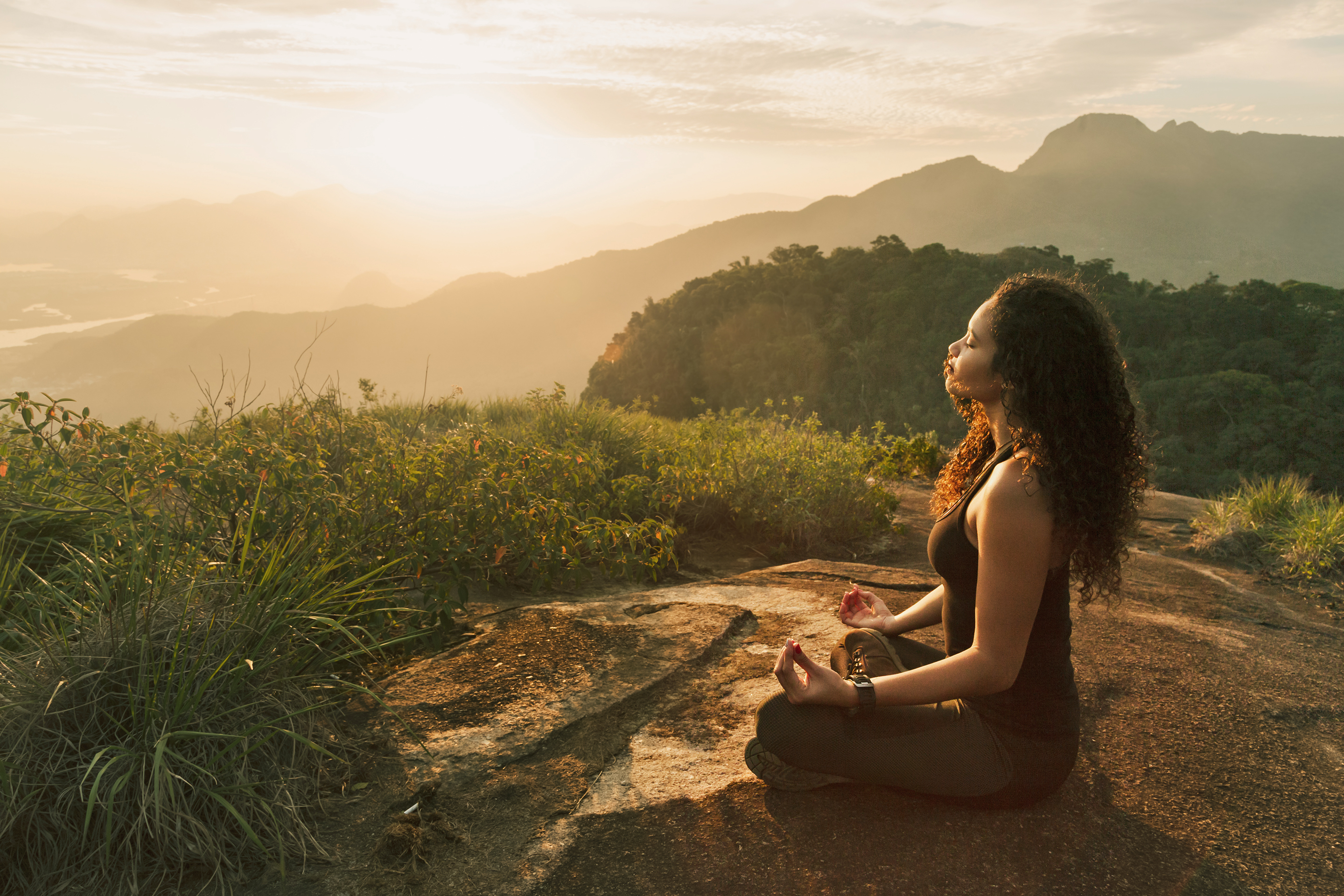 Woman perform sitting yoga pose outside as the sun sets