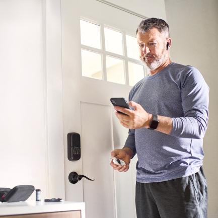 Man standing checking his phone in his left hand at home before exiting