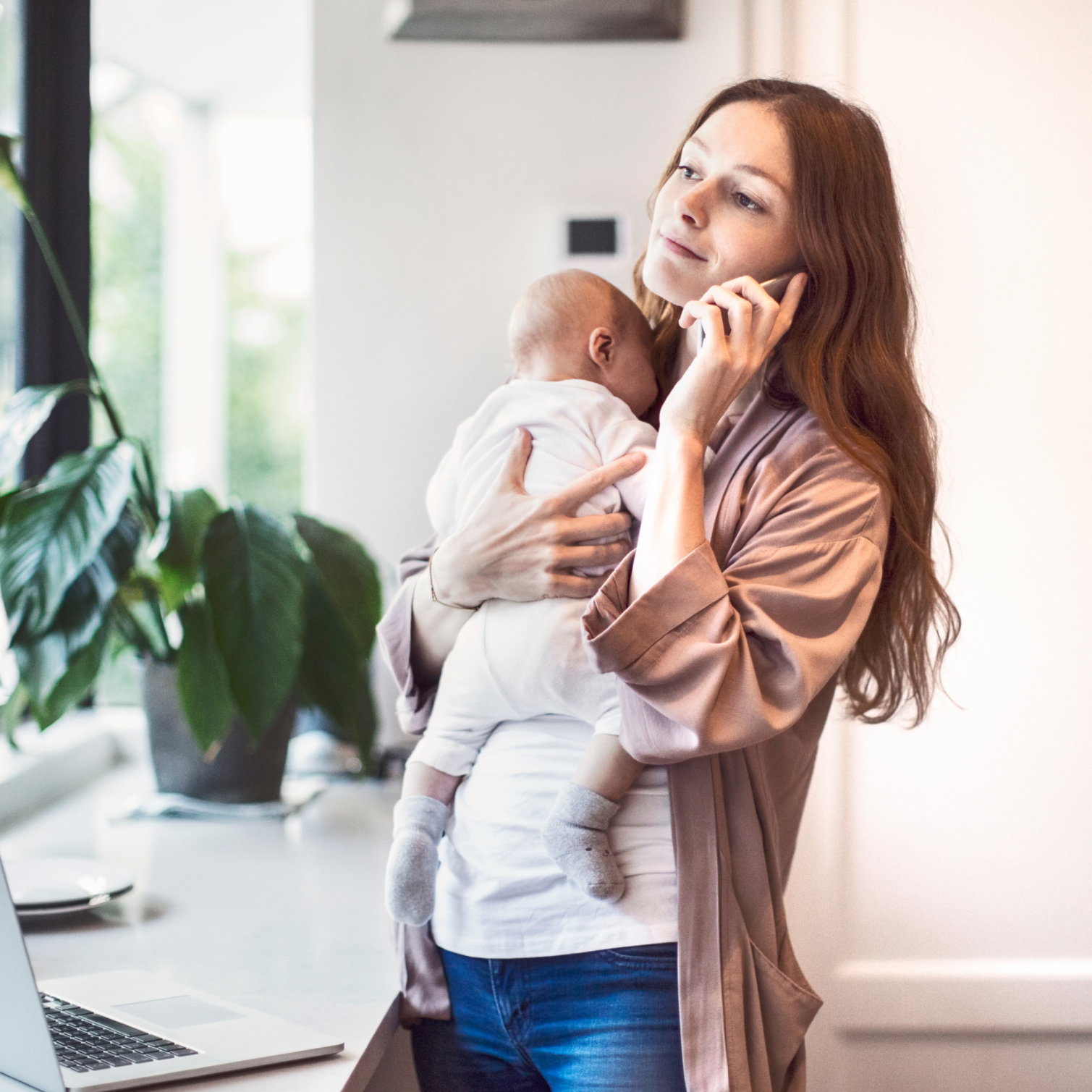 Mother standing and holding infant and cell phone