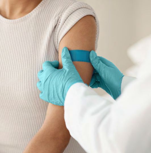 Medical professional places blue bandage on patient left arm