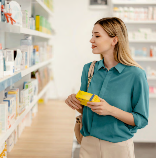 Woman shops inside pharmacy holds small yellow package