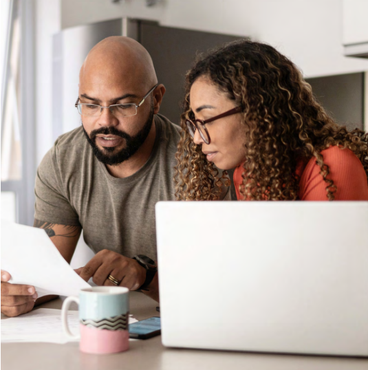 Couple both wearing eyeglasses review document near laptop