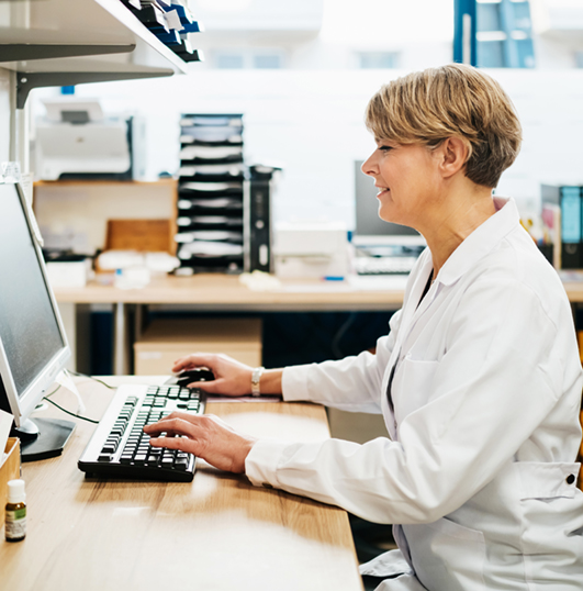 pharmacist in a large office reviewing data on her computer