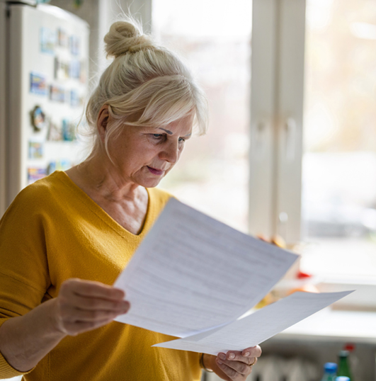 woman in her kitchen reading a letter