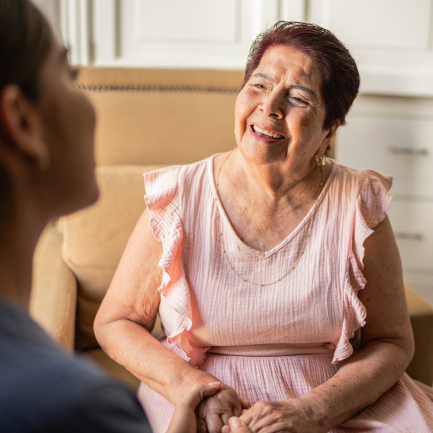 Woman in pink blouse laughing with caregiver in foreground