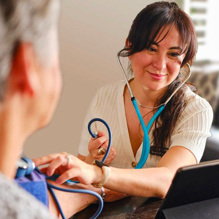 Nurse times and listens to patient's pulse with stethoscope