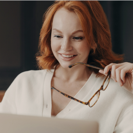 Smiling woman holds eyeglasses in left hand