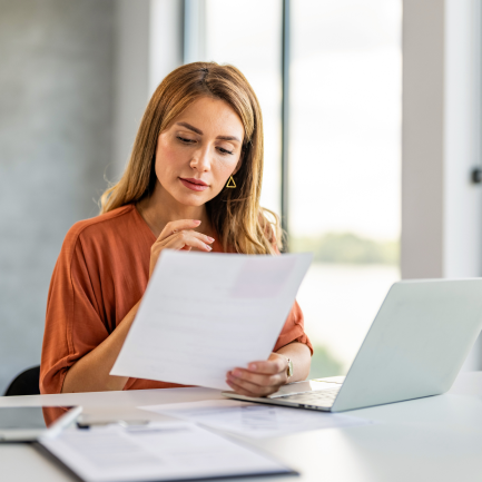 woman looking at sheet of paper in her hand