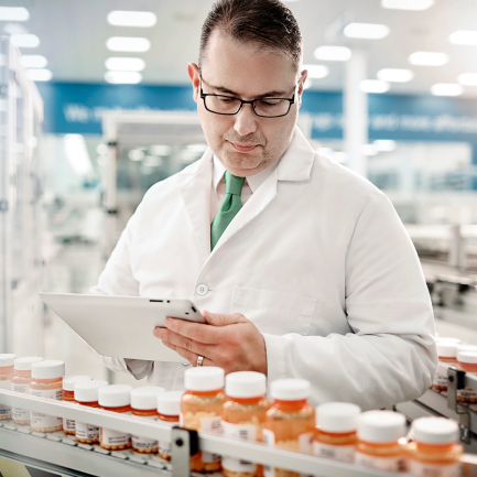 pharmacist looks over tablet to count prescription bottles