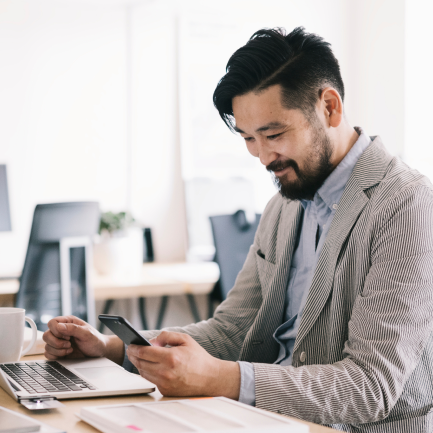 Smiling man looks down at smart phone