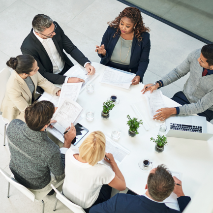 Birds-eyed view of seven adults talking around a conference room