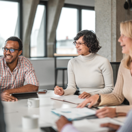 Three colleagues laughing and sitting around conference room