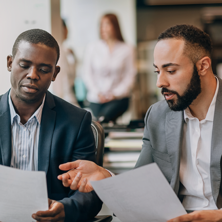 Two people sit and review documents together