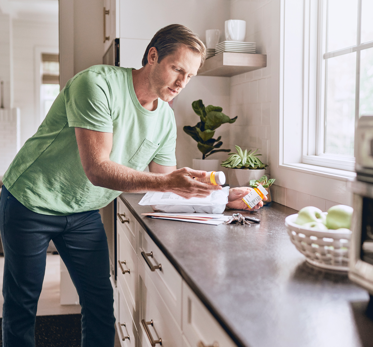 A man looks at prescription pill bottles in his kitchen