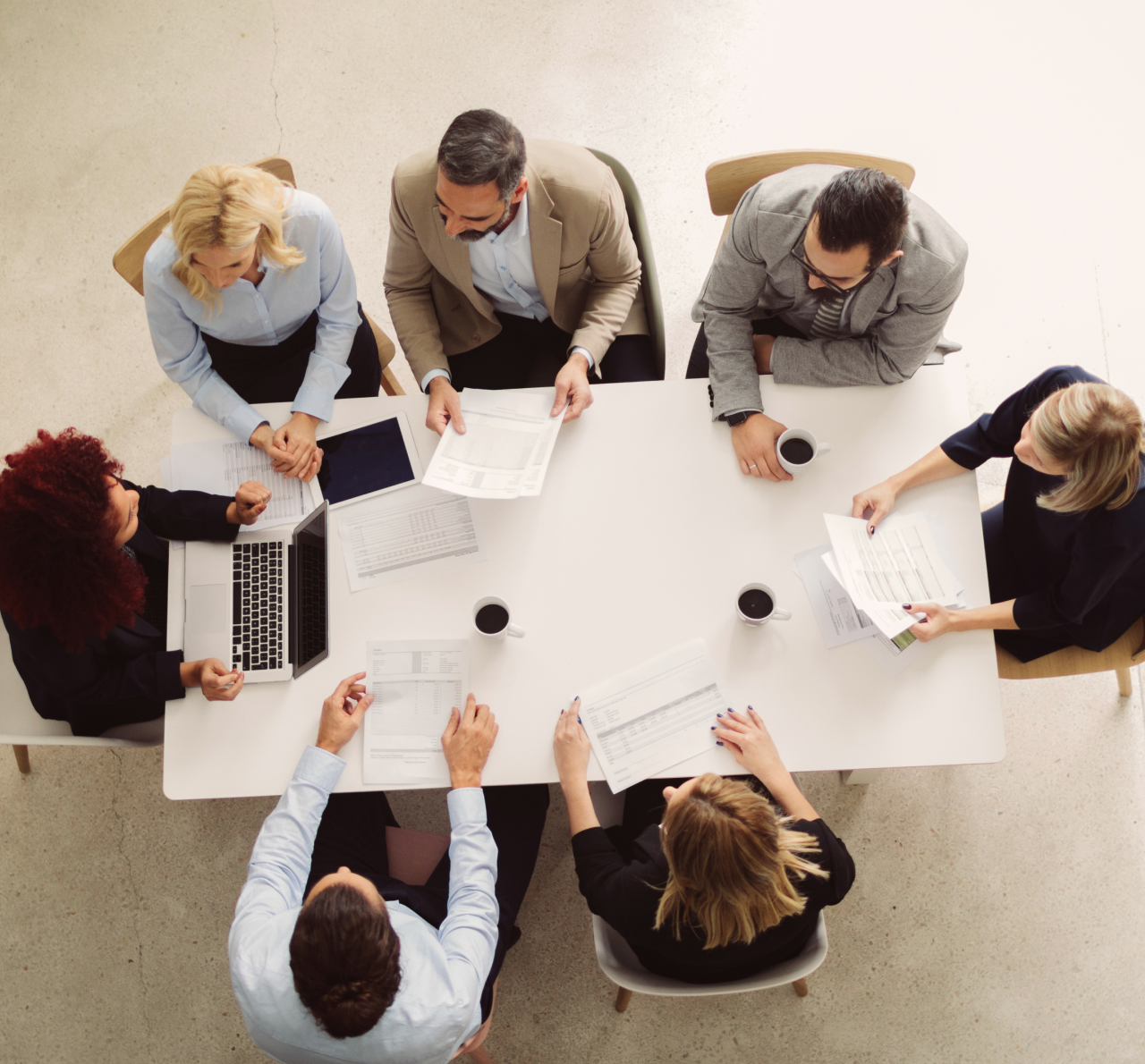 Colleagues sit around a conference table and conduct a meeting