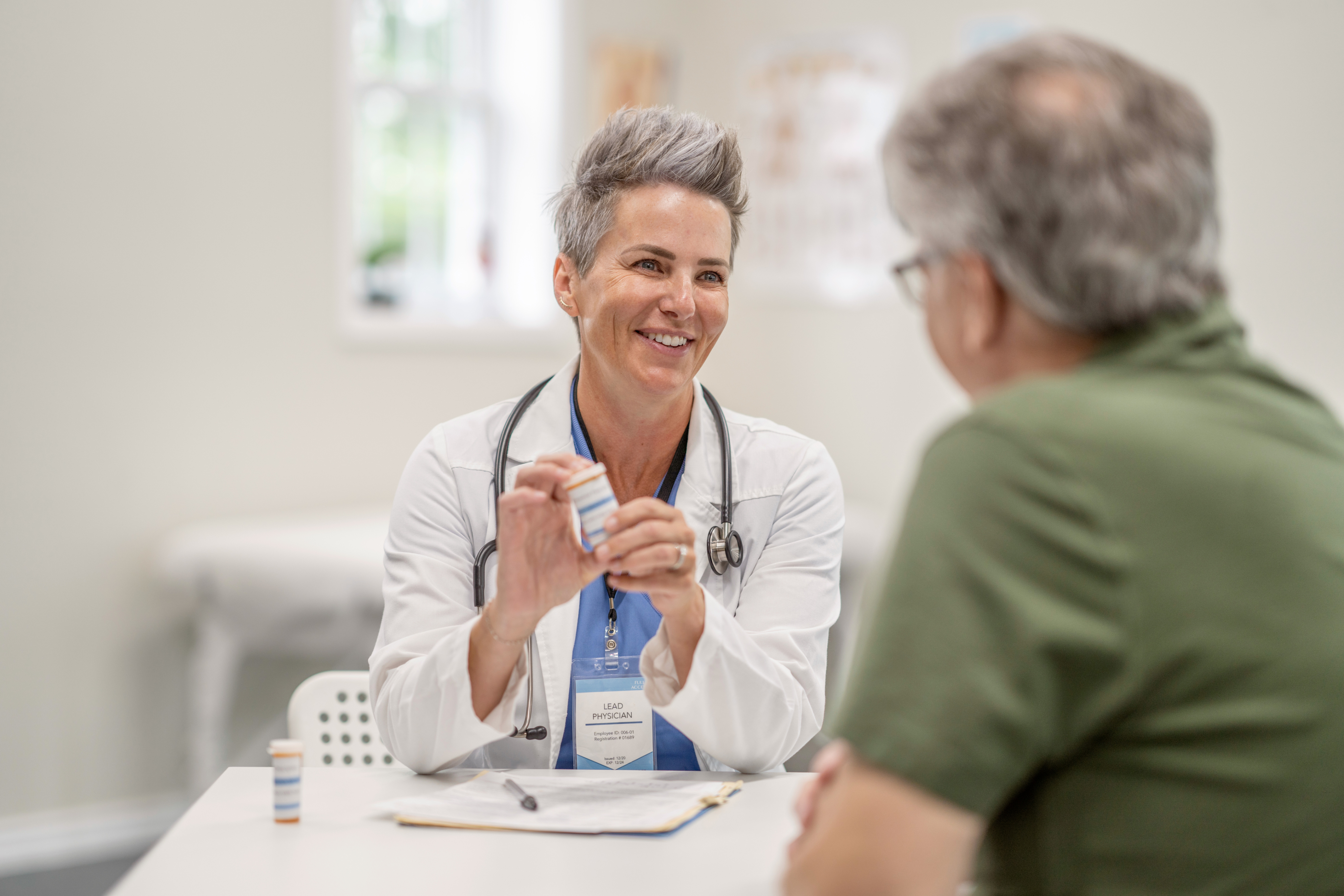 Female physician with pill bottle talking to male patient