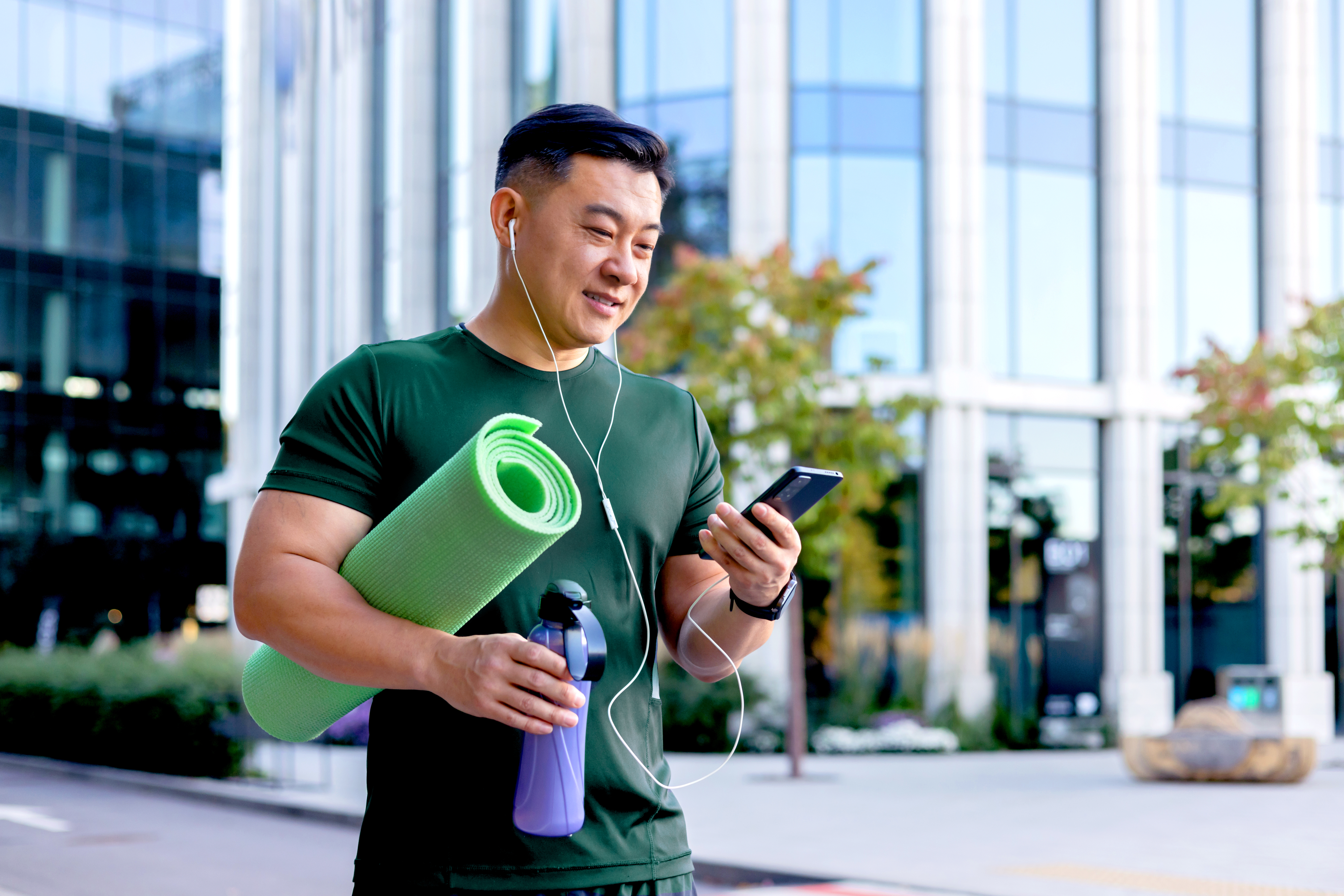 man with yoga mat with phone