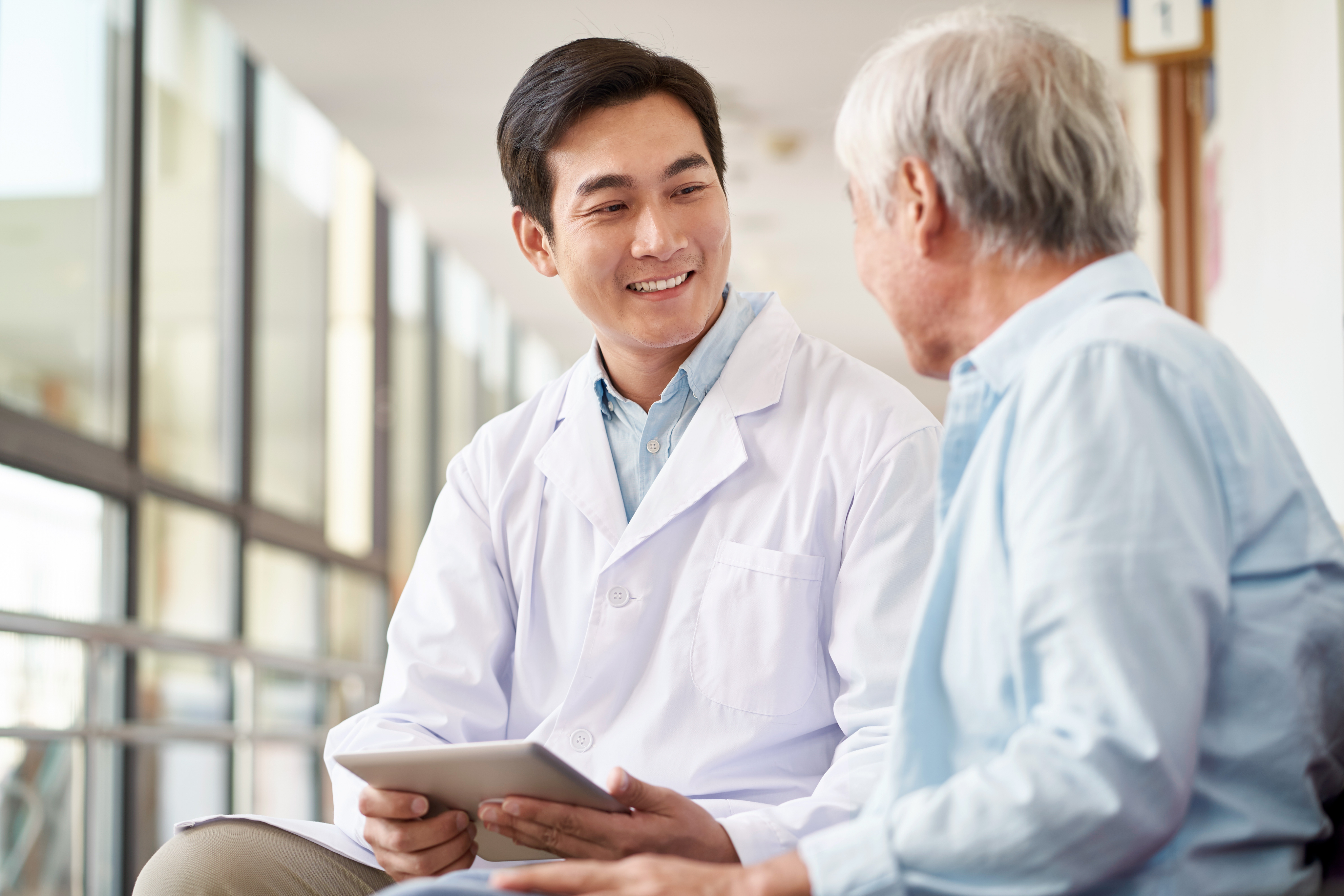 Asian male physician speaking to elderly Asian male patient