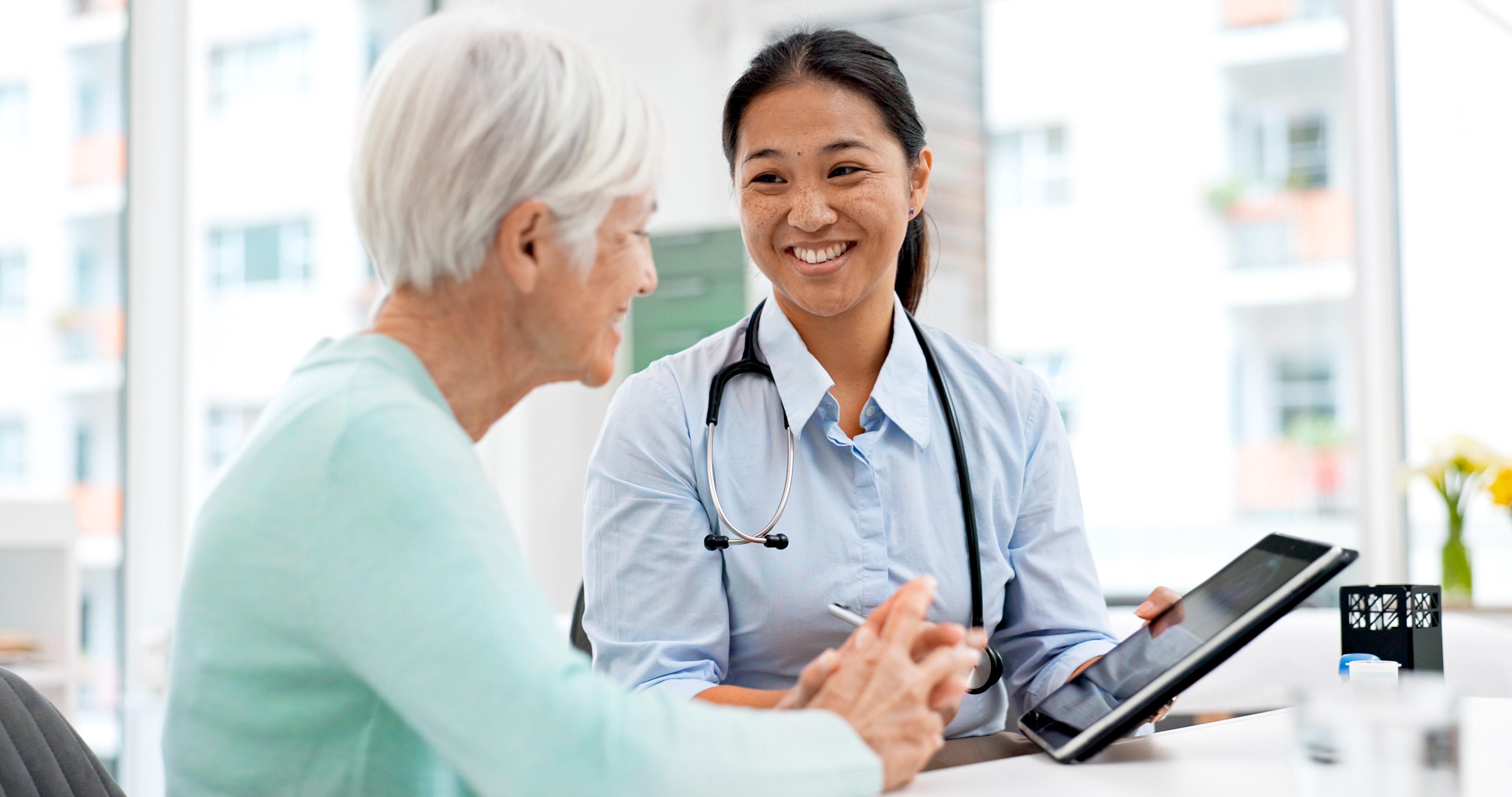 elderly senior woman with female doctor with tablet