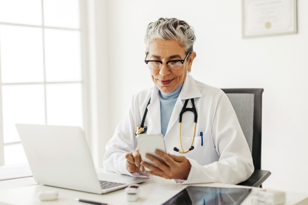 health care provider at her desk, checking mobile device