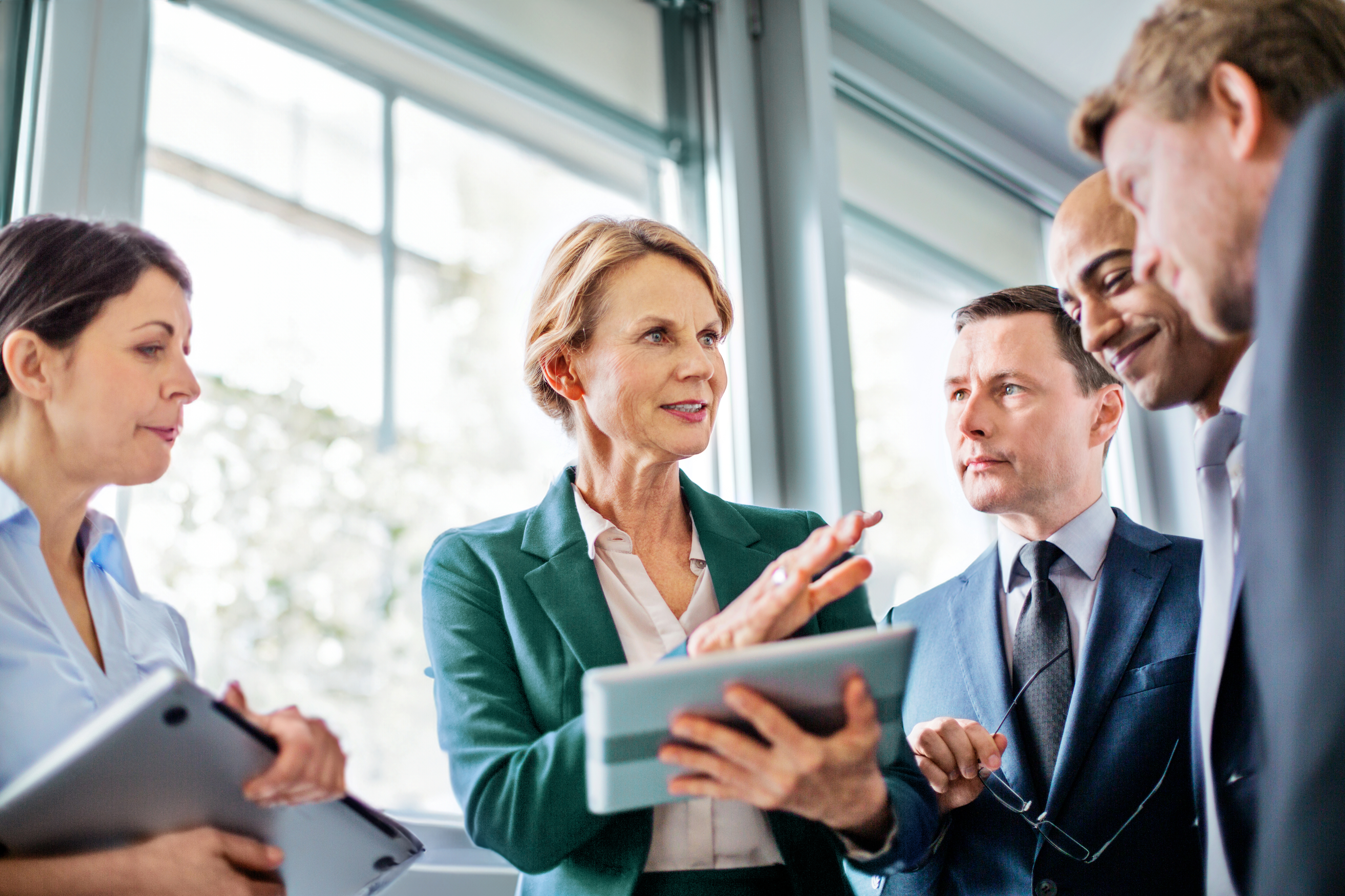 Older woman talking to men with tablet