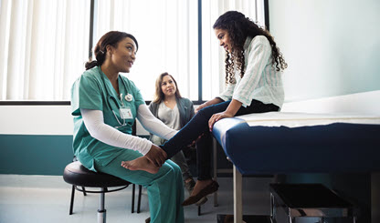 health care provider checks the lower leg of her young patient