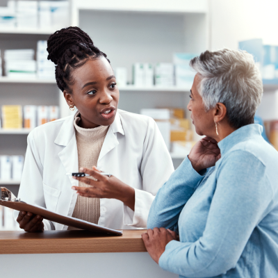 A pharmacist holding a clipboard and talking to her patient