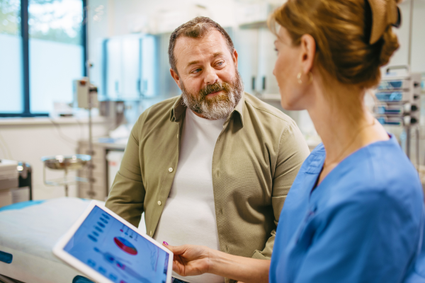 A man speaking with his health care provider, who is showing him something on her tablet