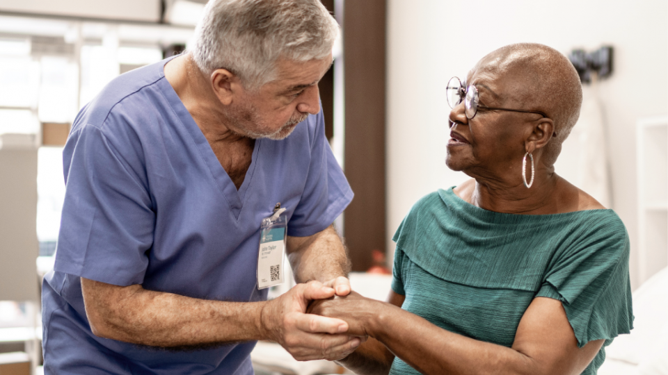 Nurse comforting his patient by holding her hand.