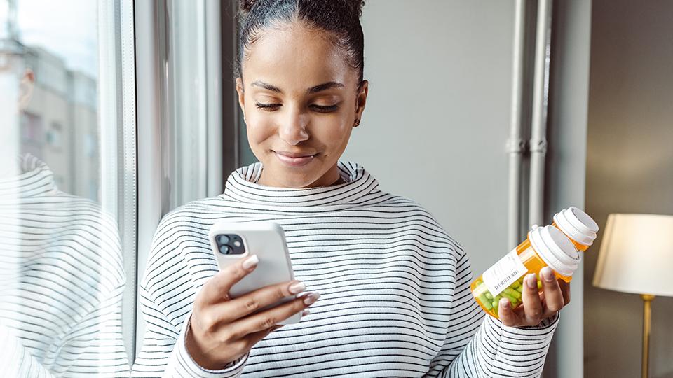 Woman looking at phone and medication