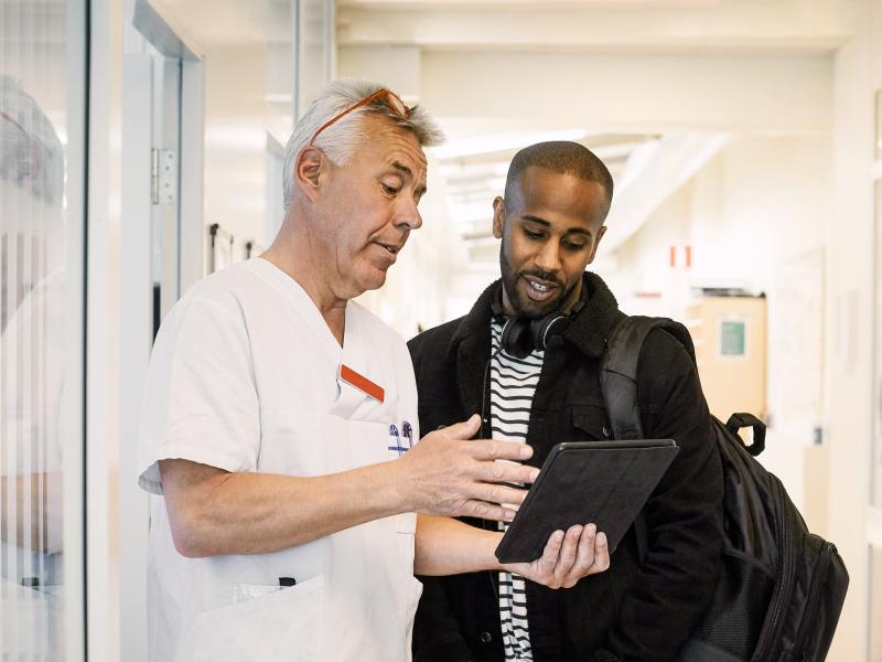 A clinician and his patient review notes on a tablet.