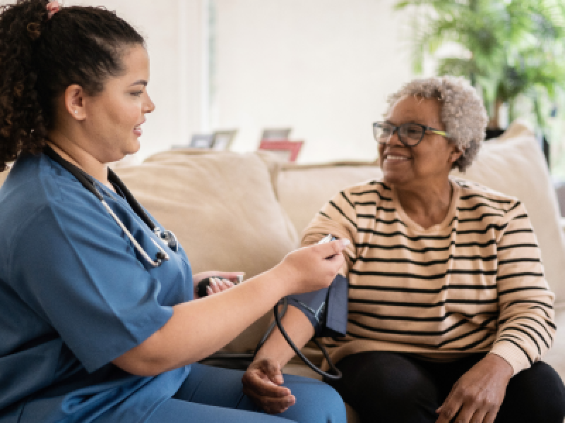 visiting nurse checks woman's blood pressure