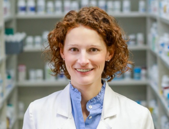 Image of Dr. Stephanie Smith Cooney standing in a pharmacy wearing a lab coat