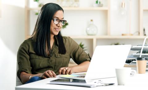 Woman smiling and looking relaxed while taking a survey on her laptop computer.