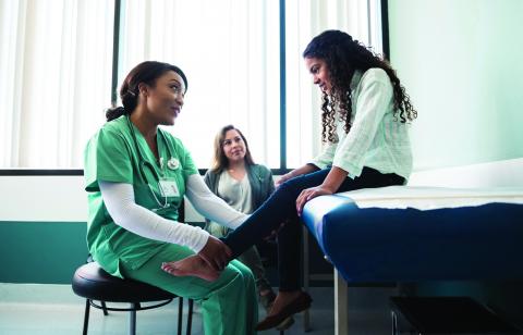 physician examining the ankle of her young patient