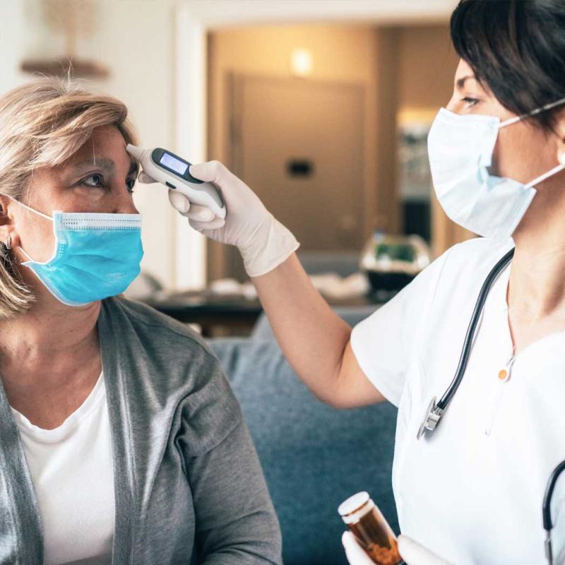 mask wearing patient's temperature being taken by mask wearing doctor