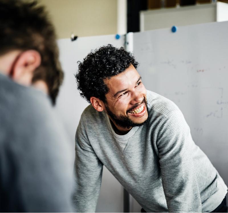 Smiling man standing in front of whiteboard presentation.