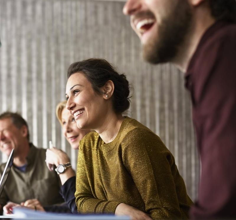 Focus on smiling woman among a group of people in a meeting.