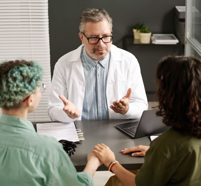 Couple holds hands and speaks to doctor