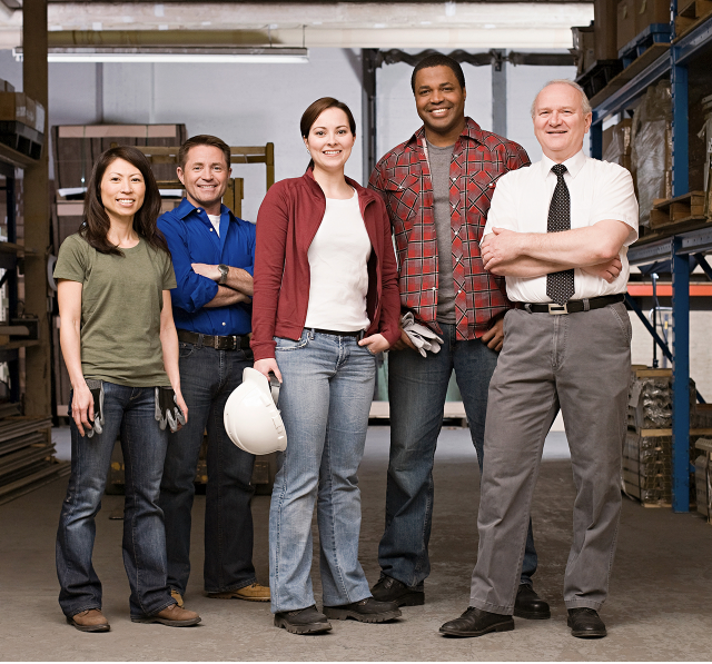 Five adults smiling and standing on warehouse floor