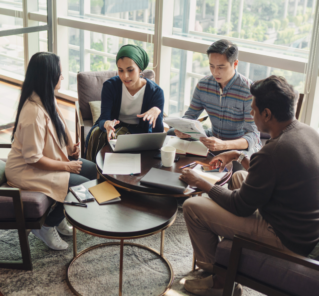 Four diverse adults conferring around two small circular tables