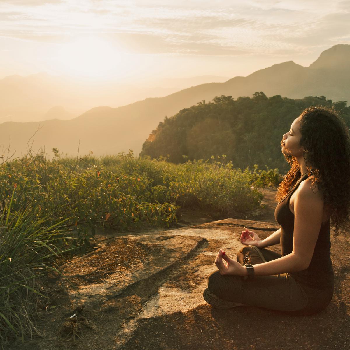 Woman perform sitting yoga pose outside as the sun sets