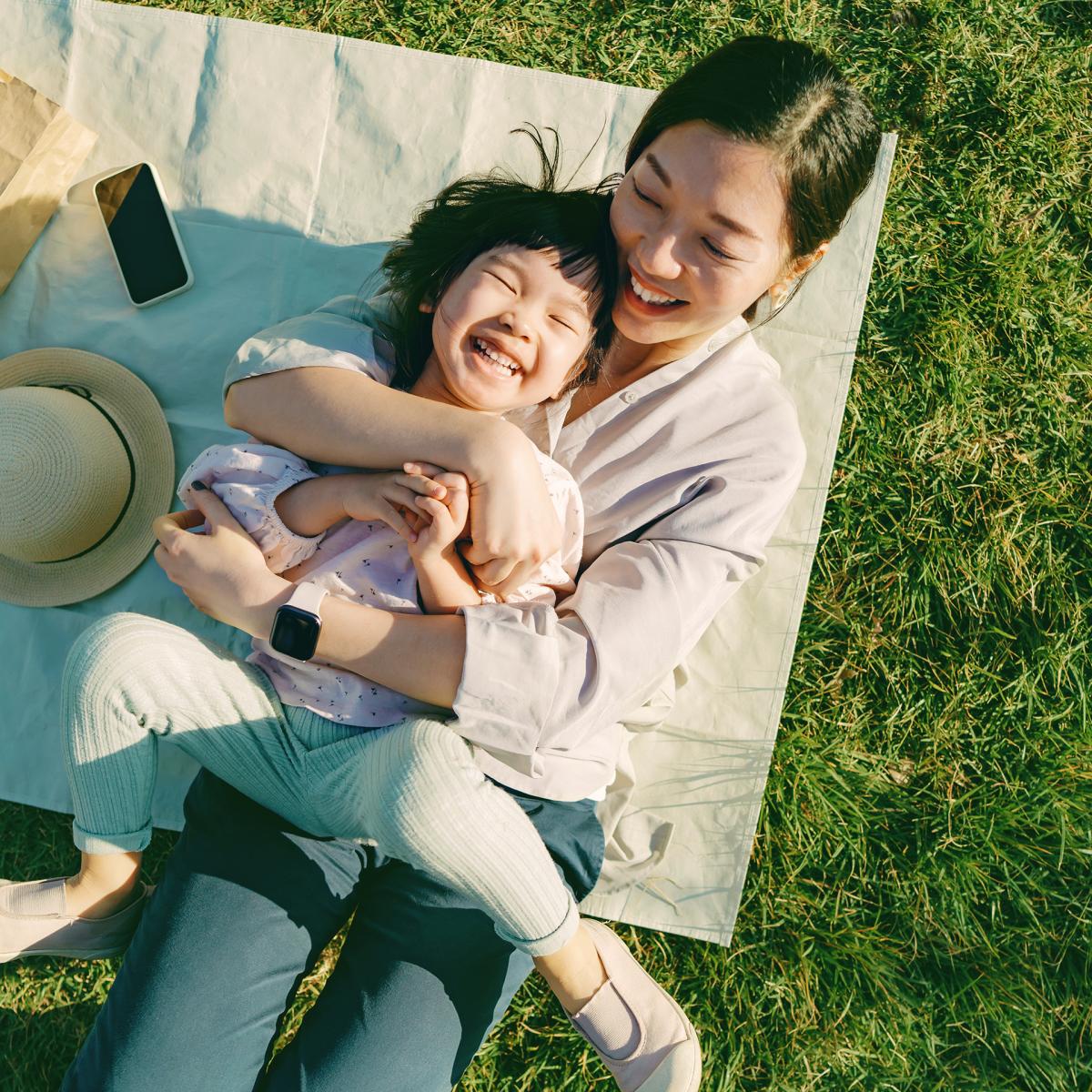 Mother holding her young daughter and laughing.