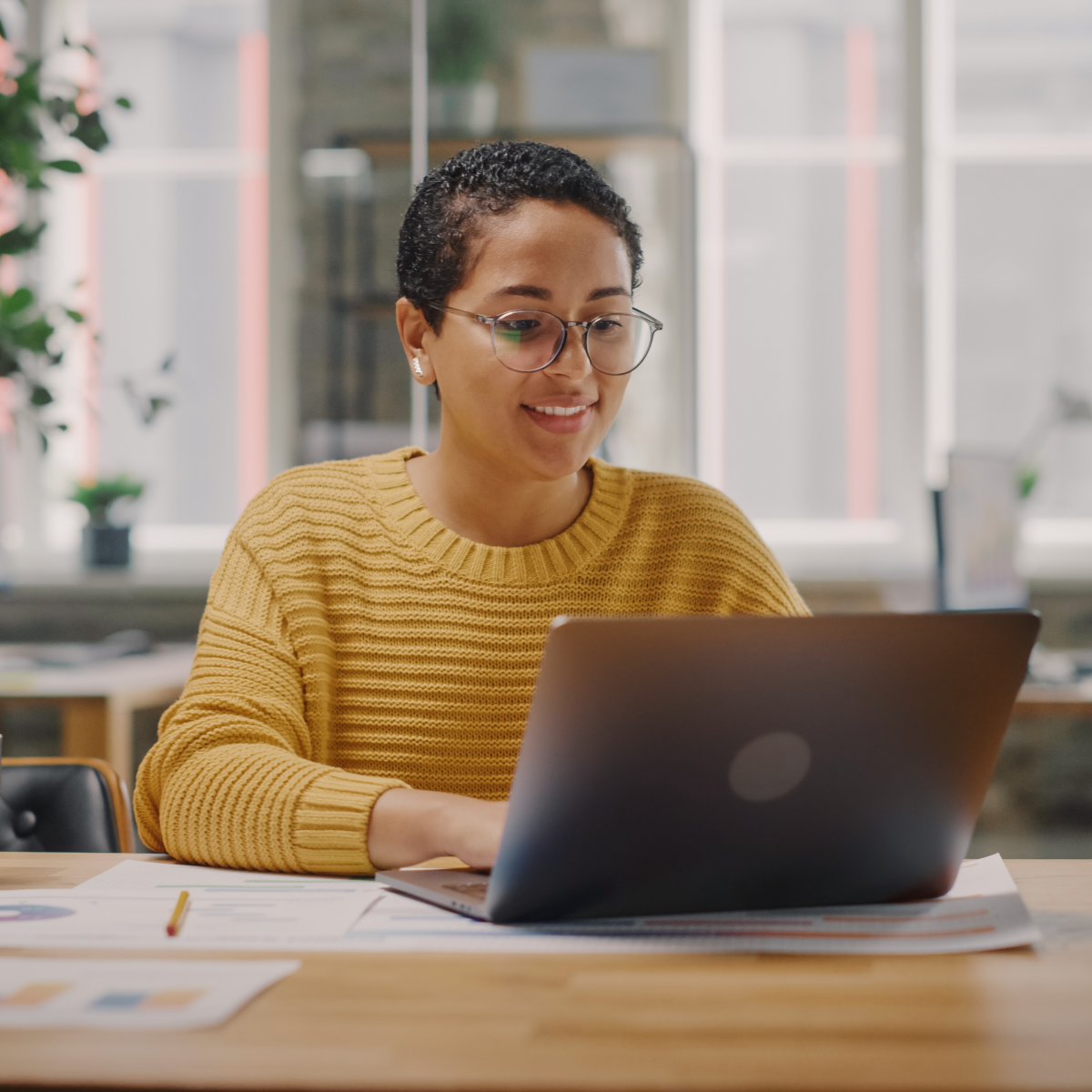 Woman in modern office setting, working at a laptop computer.