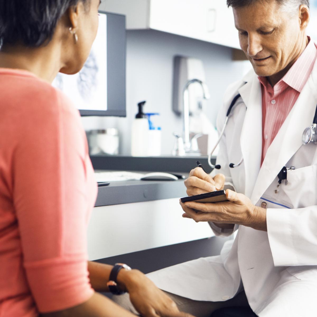 doctor writing instructions for a patient during consultation