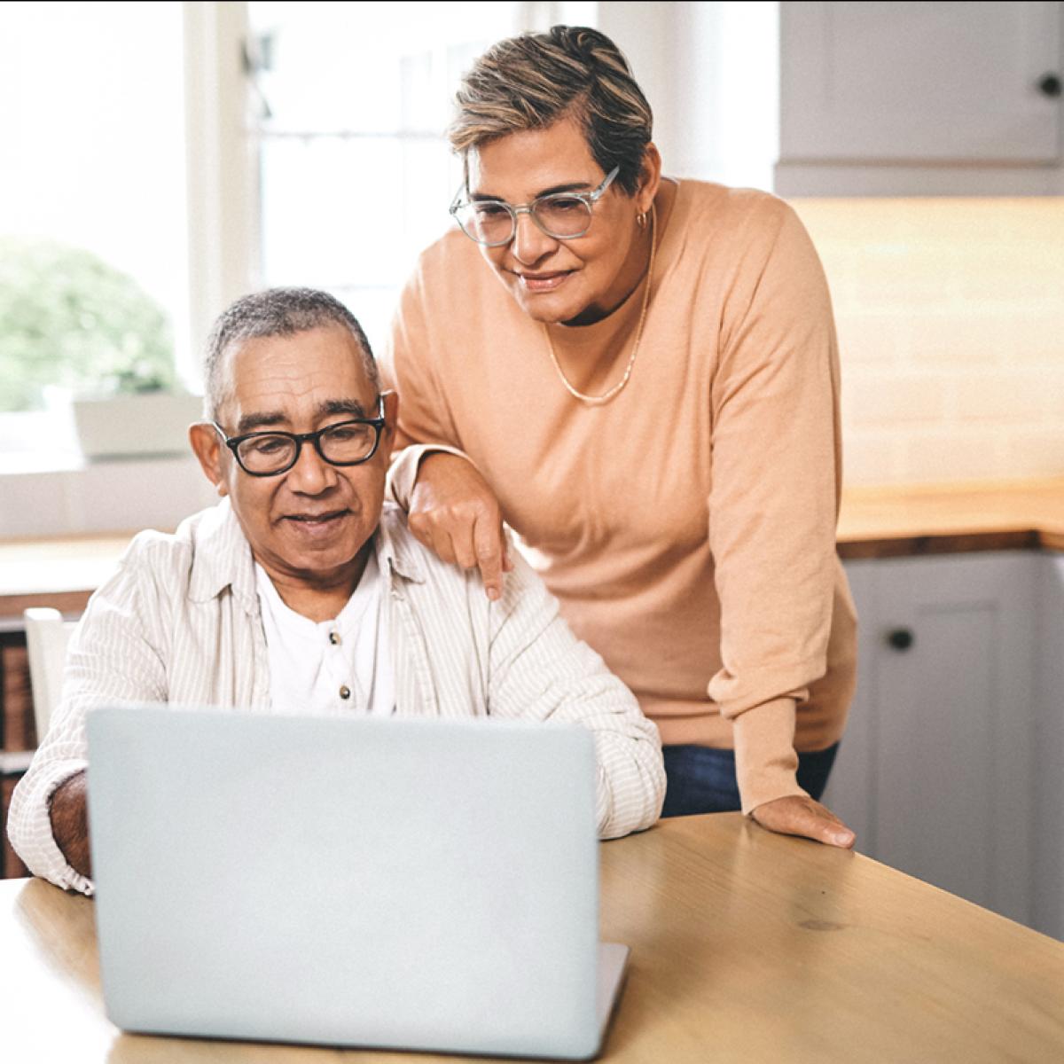 Couple in kitchen looking at laptop