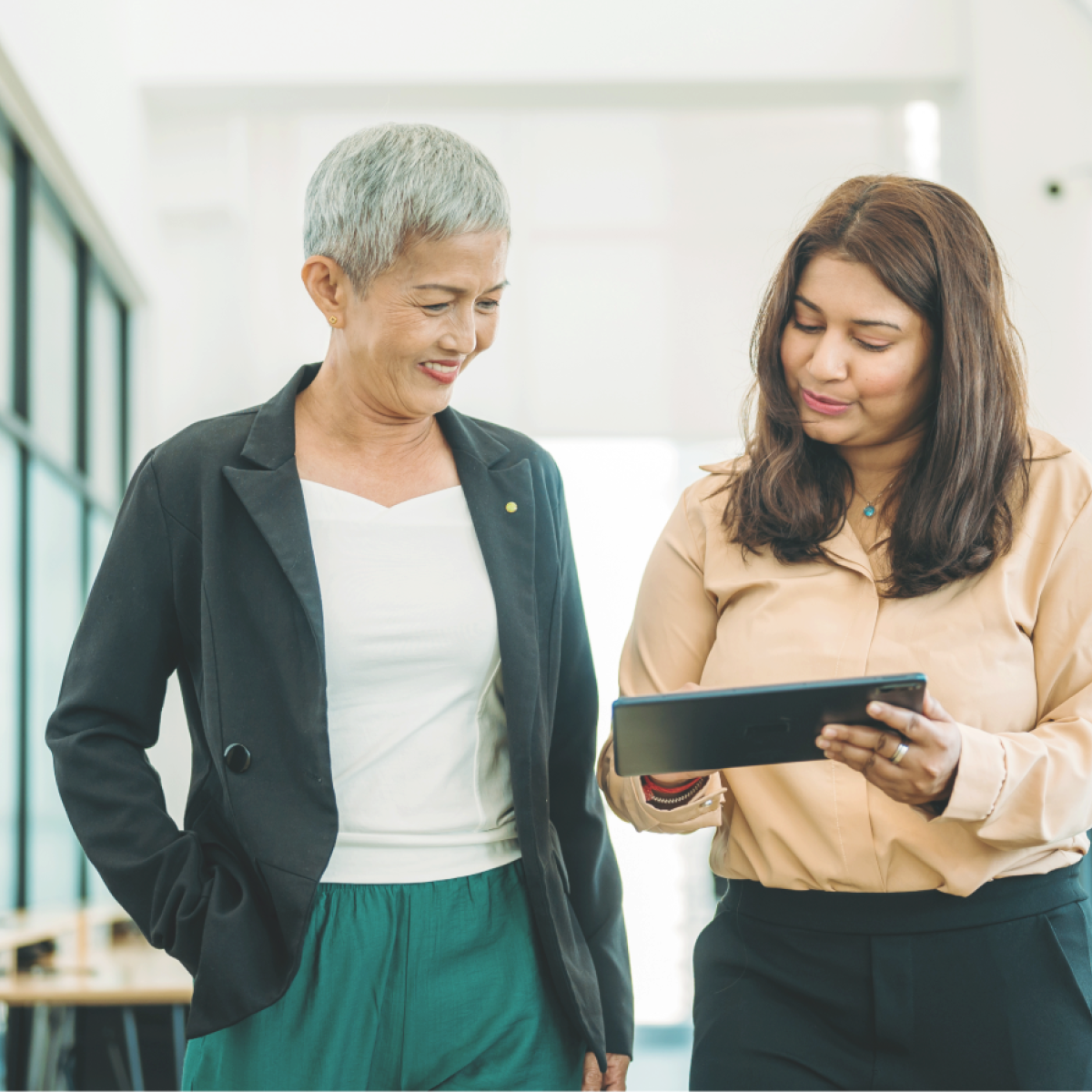 Colleagues discuss content on a tablet while walking together