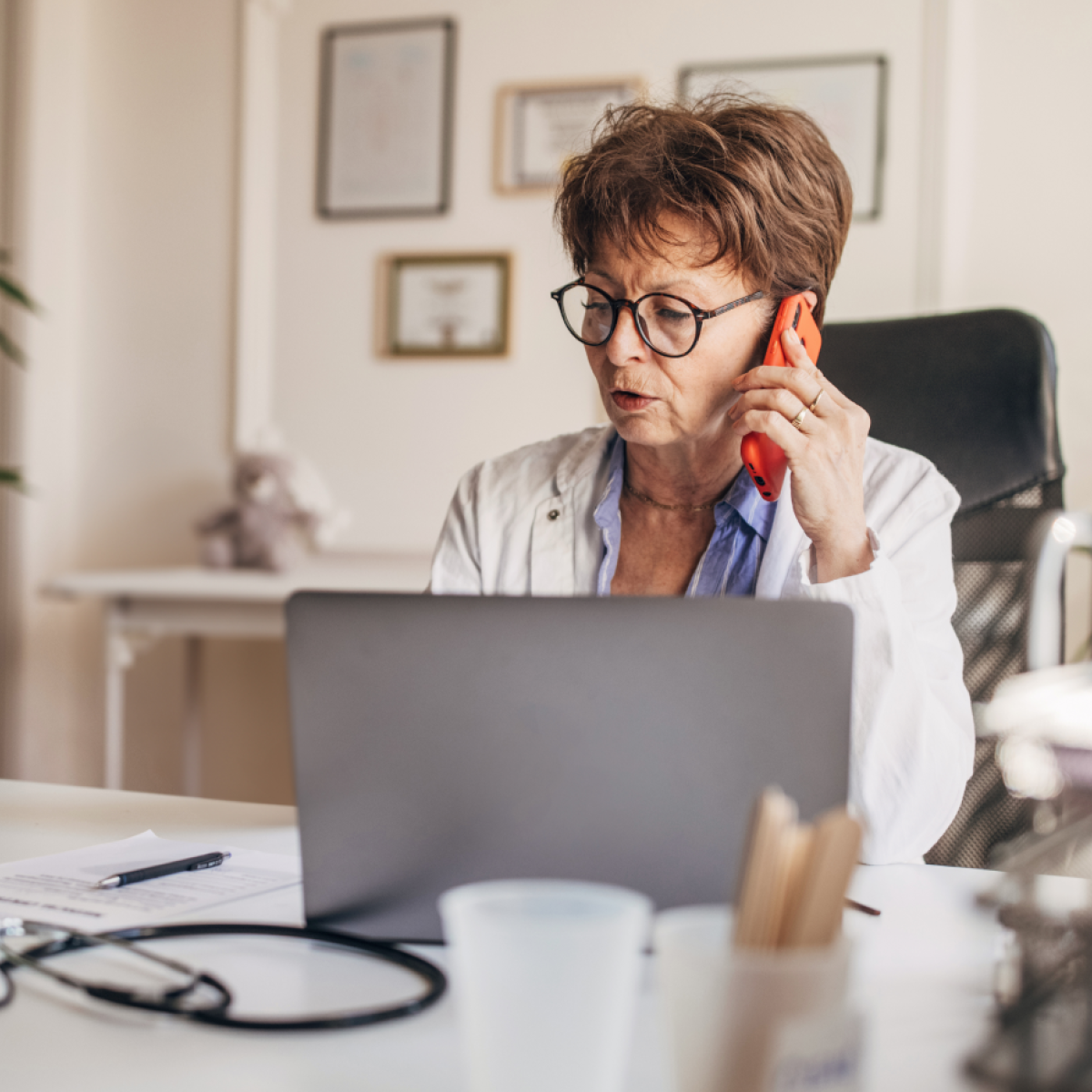 A physician uses a laptop while speaking on the phone.