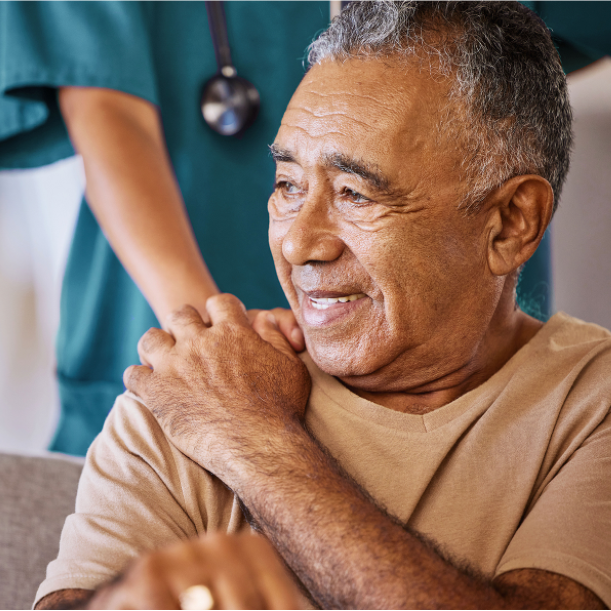 Smiling man holds caregiver's hand over his shoulrder